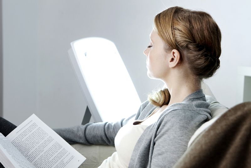Eine Frau sonnt sich Zuhause mit Lichttherapie.