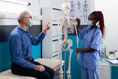 Medica informa un paziente con uno scheletro anatomico