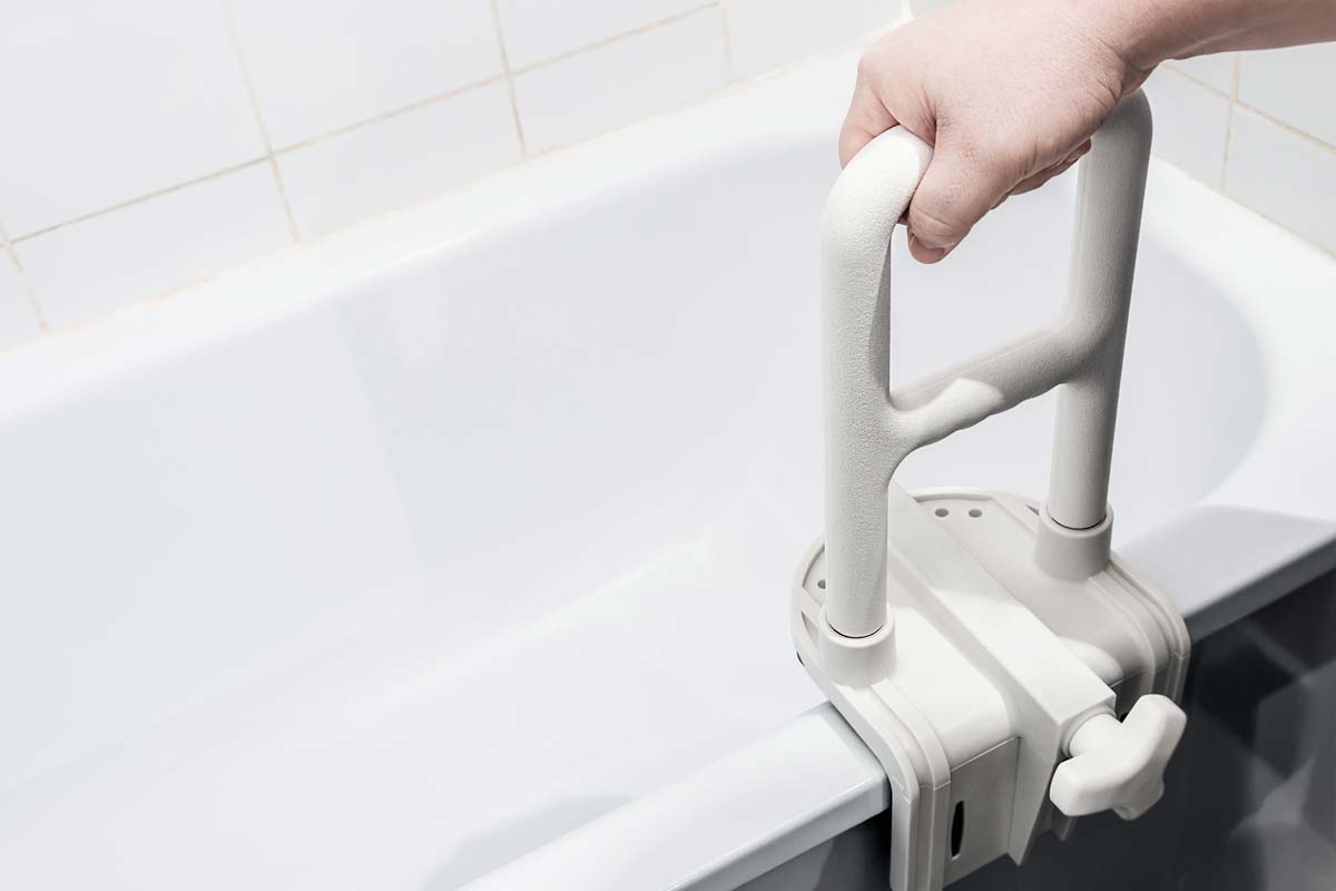 Mano che si tiene alla maniglia di sostegno per una vasca da bagno