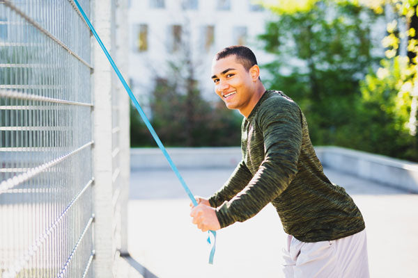 Uomo che si allena con un elastico Theraband fissato