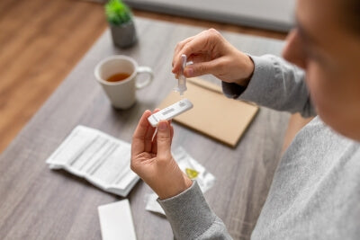 Una donna esegue un test diagnostico rapido a domicilio su un tavolo
