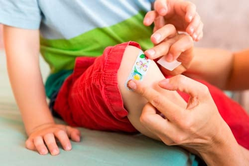 Un cerotto colorato per bambini viene applicato sul ginocchio di un bambino