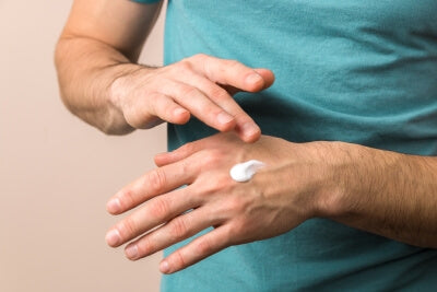 Primo piano di un uomo che applica schülke Skin Care sulle mani